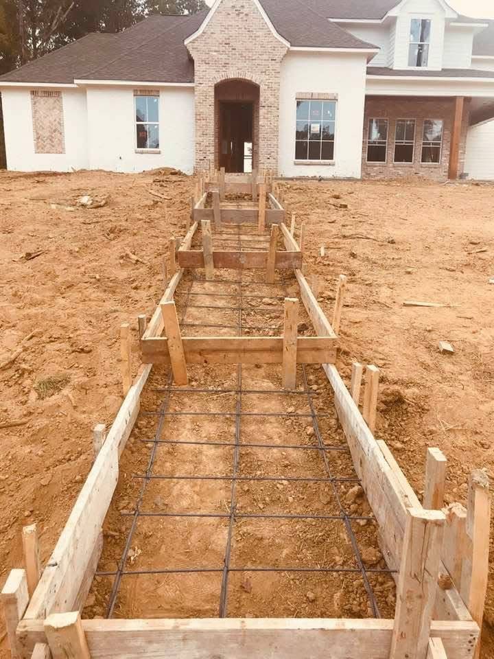 Foundation forms and rebar leading toward a house